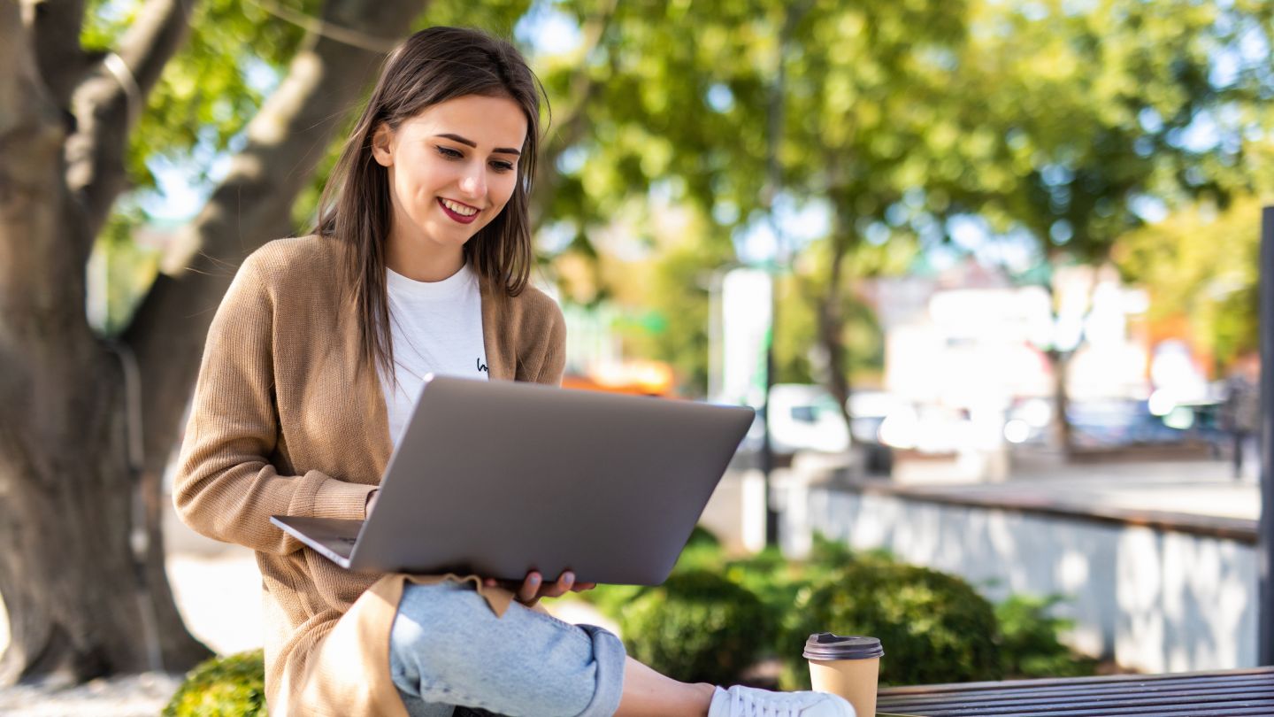 Happy teacher using her laptop to successfully integrate an AI teaching assistant on a beautiful day