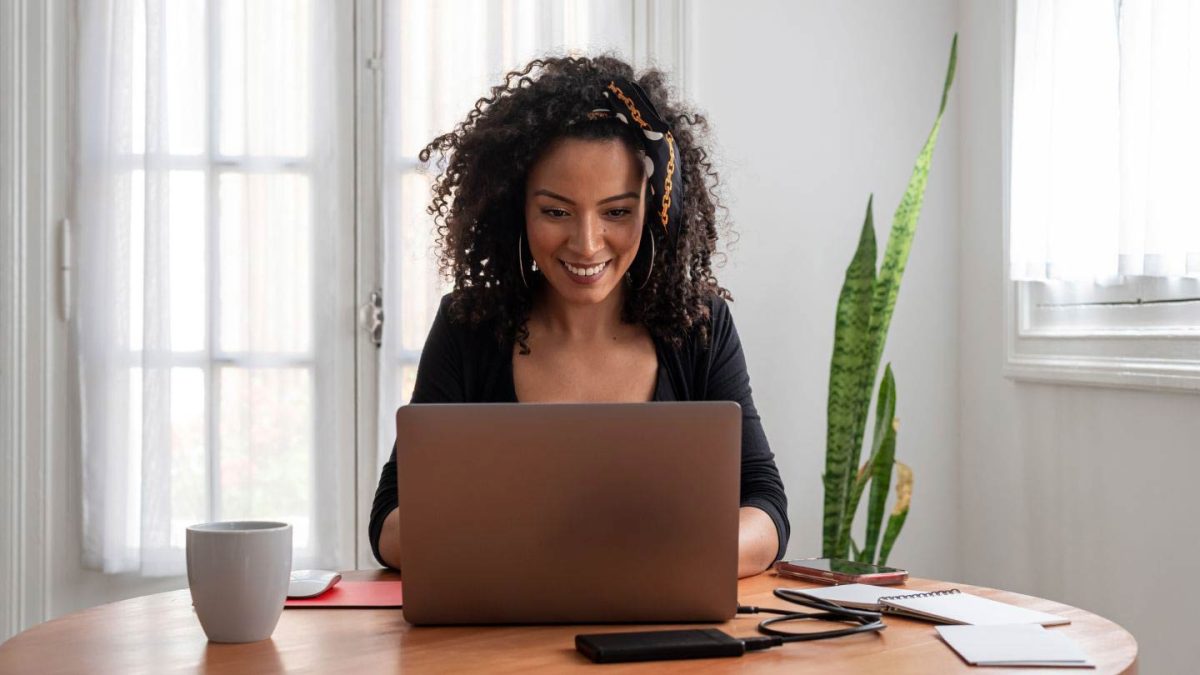 Smiling teacher using a laptop with an AI writing assistant to grade papers and assign homework, looking delighted and engaged.